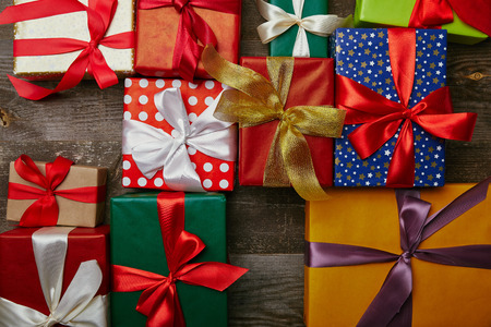 flat lay with christmas presents wrapped in different wrapping papers with ribbons on wooden surfaceの写真素材