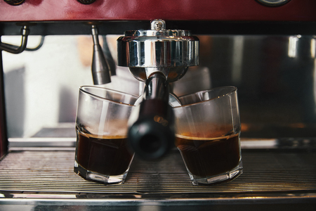 close-up view of two glasses and coffee machine preparing espressoの写真素材