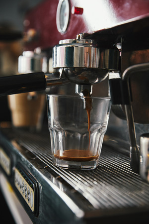 professional coffee maker and glass cup with espresso in coffeehouseの写真素材