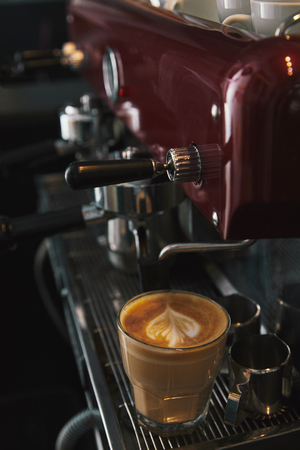 close-up view of coffee machine and glass cup with cappuccinoの写真素材