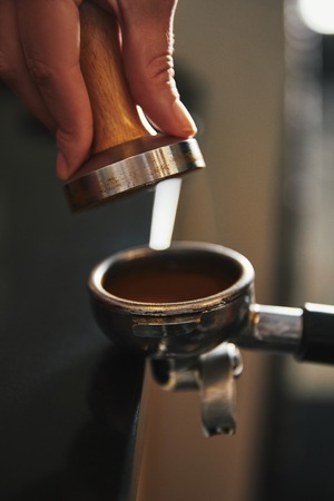 cropped shot of barista preparing coffee in coffee maker