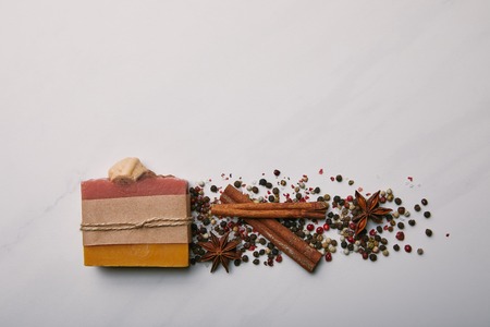 top view of handmade soap with anise, coffee beans and cinnamon sticks on white marble surfaceの写真素材