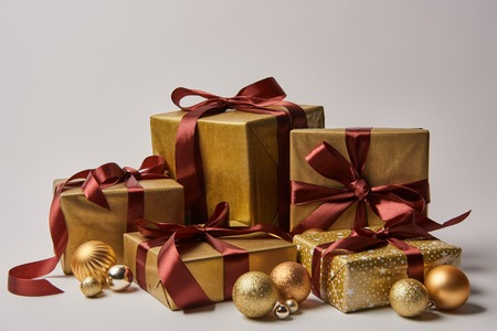 golden Christmas gift boxes with burgundy ribbons and baubles isolated on white