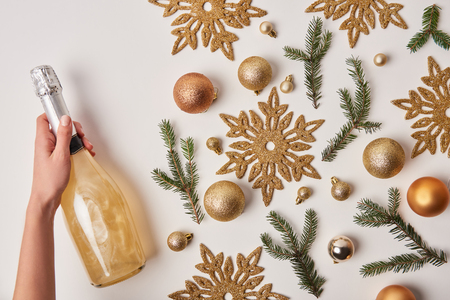 cropped image of woman holding bottle of sparkling champagne near christmas decoration isolated on whiteの写真素材