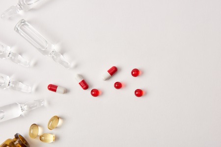 top view of various pills and ampoules with medicament on white surface