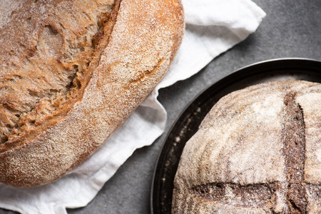 top view of loafs on baked bread on linen and plate on grey surfaceの写真素材