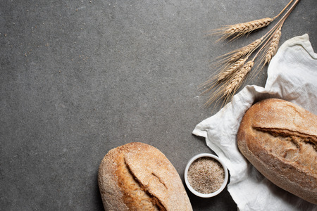 flat lay with arranged bread and wheat on grey tabletopの写真素材