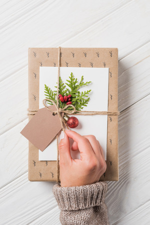 partial view of woman decorating christmas gift box at wooden tableの写真素材