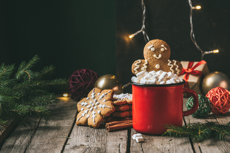 gingerbread man in cup of cocoa with marshmallows on wooden table with christmas light garlandの写真素材