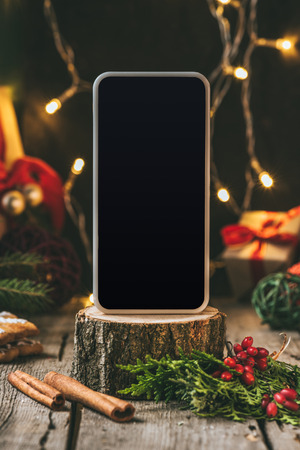 smartphone with blank screen on wooden stump with christmas decorの写真素材