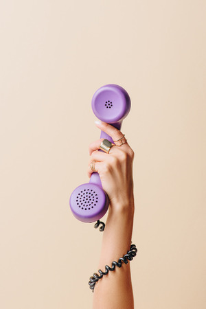 partial view of woman holding purple phone tube on beigeの写真素材