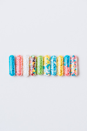 top view of row of various colorful medical capsules on white