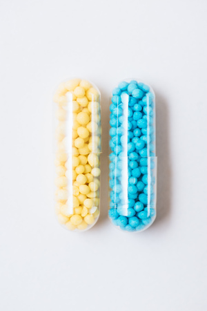 top view of blue and yellow medical capsules on white