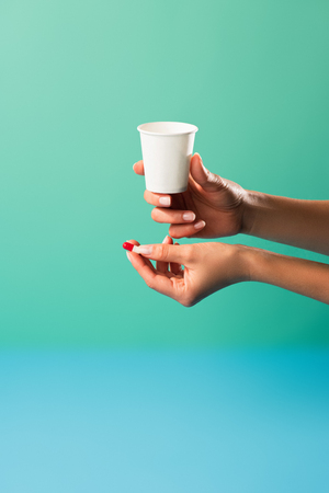 cropped shot of person holding small cup and medical capsule isolated on greenの写真素材