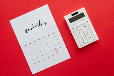 top view of calendar for November and calculator isolated on red, black friday conceptの写真素材