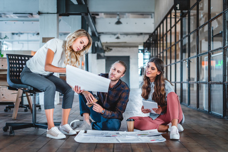 young coworkers sitting together and working with business charts in office