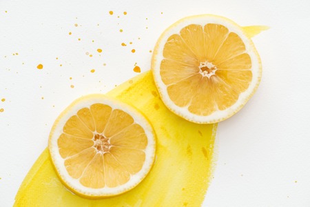 top view of citrus pieces on white surface with yellow watercolorの写真素材
