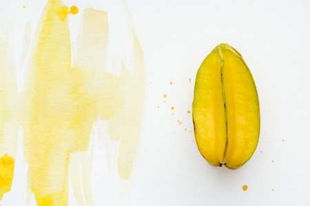 top view of tasty exotic carambola on white surface with yellow watercolorの写真素材