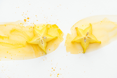 top view of two star fruits on white surface with yellow watercolorの写真素材