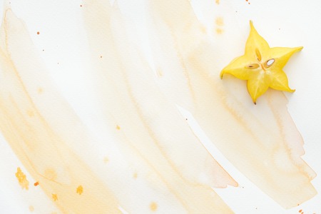 top view of one ripe star fruit on white surface with yellow watercolorの写真素材