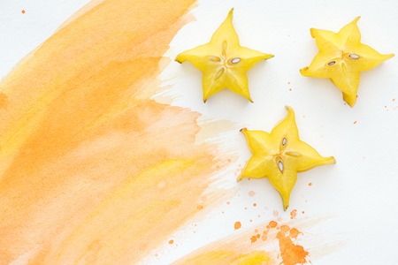 top view of star fruits on white surface with orange watercolorの写真素材