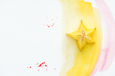 top view of carambola on white surface with yellow and pink watercolorsの写真素材