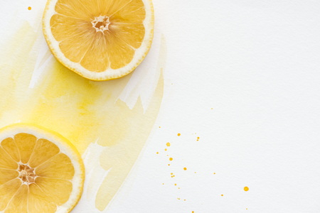 top view of yummy lemon pieces on white surface with yellow watercolorの写真素材