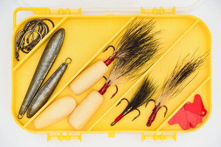 elevated view of plastic yellow box with various fishing hooksの写真素材
