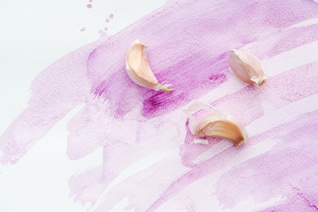 top view of spicy raw garlic on white surface with pink watercolor strokesの写真素材