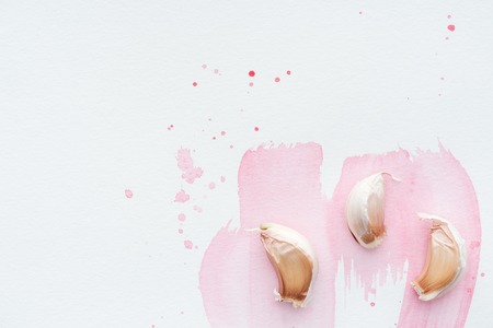 top view of spicy garlic on white surface with pink watercolor strokesの写真素材