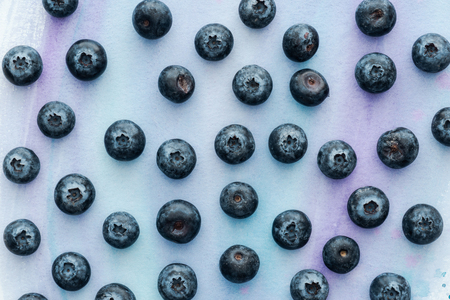 top view of ripe blueberries on white surface with purple watercolor strokesの写真素材