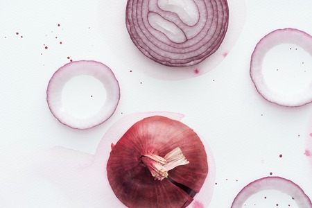 top view of sliced spicy red onion on white surface with pink watercolor blotの写真素材