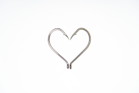 flat lay with heart symbol made of fishing hooks isolated on white
