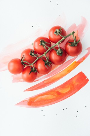 top view of branch of ripe cherry tomatoes on white surface with red watercolor strokesの写真素材