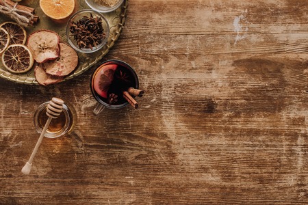 top view of cup of mulled wine and honey on wooden table