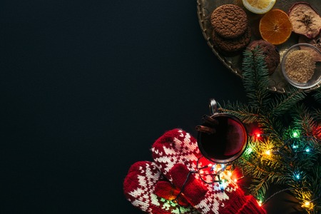 top view of cup of mulled wine, garland, mittens and cookies isolated on black, christmas conceptの写真素材