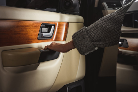 partial view of woman closing car door while sitting in carの写真素材