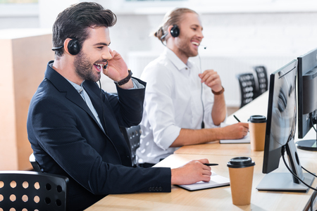 side view of male call center operators in headsets at workplace in officeの写真素材