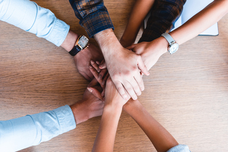 partial top view of young business team stacking hands at workplaceの写真素材