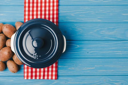 top view of pan and potatoes on blue tableの写真素材