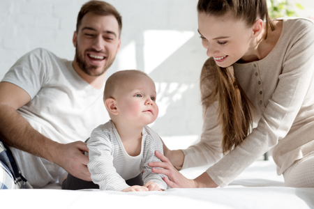 young smiling parents with little son on bed