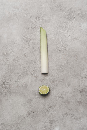 top view of exclamation mark made from leek and lime on greyの写真素材