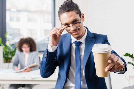 Smiling businessman offering coffee in paper cupの写真素材