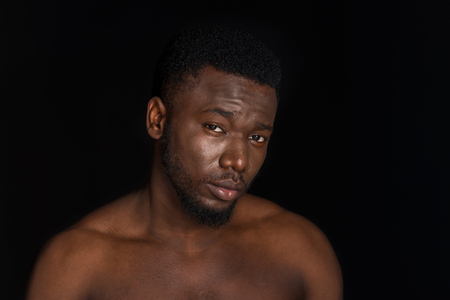 portrait of handsome young bare chested african american man looking at camera isolated on blackの写真素材