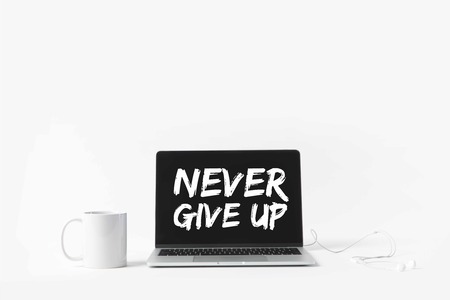 laptop with Never give up inspiration on screen, earphones and white mug, isolated on whiteの写真素材