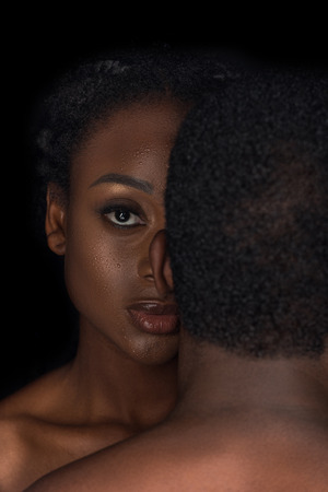 young naked african american couple posing together isolated on blackの写真素材