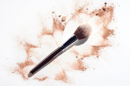 Plush make up brush on white background with scattered face powderの写真素材