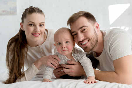 smiling parents with little boy on bedの写真素材