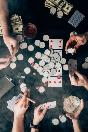 Smoke over people playing poker by casino table with cards and chipsの写真素材