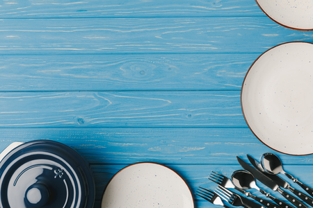 top view of plates, utensil and pan on blue tableの写真素材